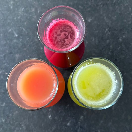 Three small glass cups filled with colorful liquids on a dark surface